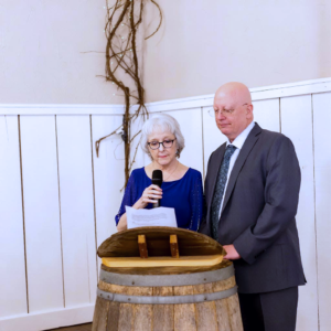 Senior family members giving speech in front of a wine barrel podium.